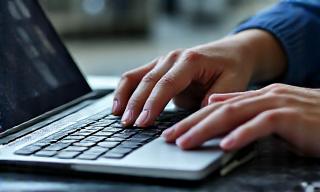 Riparazione schermo laptop danneggiato, con un tecnico che esamina delicatamente i componenti interni.